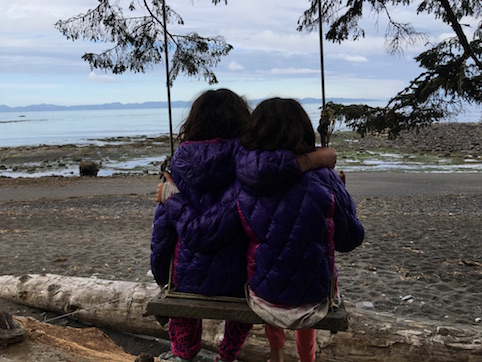 Vitamin N: Sisters on a swing looking at the ocean